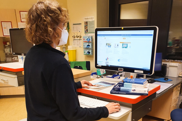 Teamomat: Pflegefachkraft arbeitet im Stehen an PC